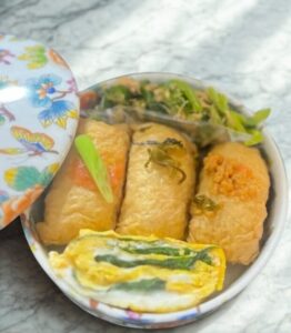 ポーセラーツで作った白磁のお重に南関いなりを盛りつけた食卓。手づくり食器が主役の日常を楽しむシーン。